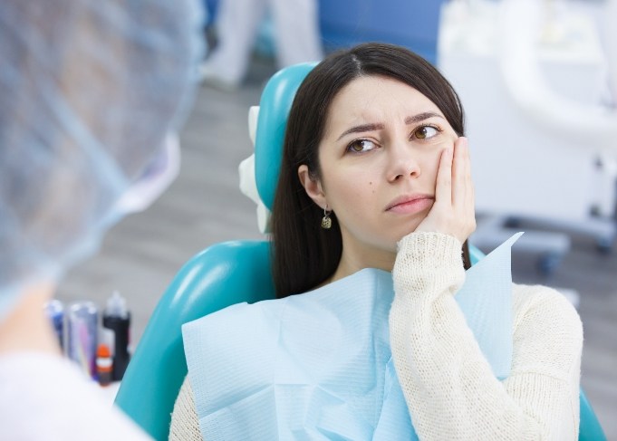 Woman rubbing her jaw visiting emergency dentist in Glastonbury