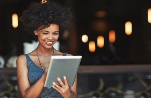 Woman standing outside looking at tablet and smiling