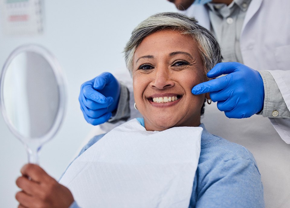 Patient smiling while holding handheld mirror