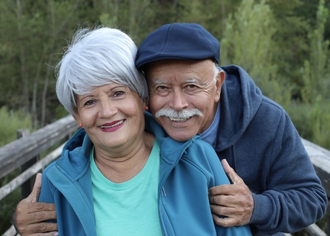 Senior couple standing in woods and smiling